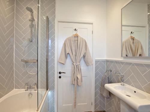 a bathroom with a sink and a robe hanging on a door at 3 Bed in Bakewell oc-90384 in Bakewell