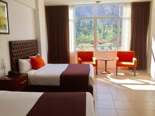 a hotel room with two beds and a window at Guizado Portillo Hacienda & Resort in Lunahuaná