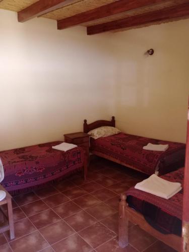 a room with two beds and a table and chairs at MiskyPacha in Purmamarca