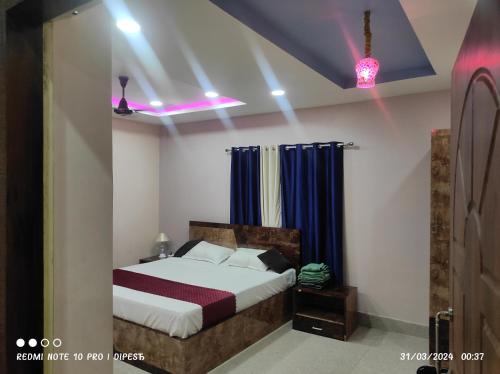 a bedroom with a bed with blue curtains at Hotel Biswal Inn in Cuttack