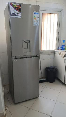 Un refrigerador de acero inoxidable en una cocina con ventana. en M&D hebergement, en Dakar