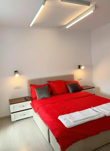 a bedroom with a large red bed and a night stand at Apartament Karim in Drobeta-Turnu Severin
