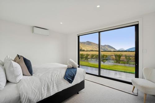 a bedroom with a bed and a large window at Rubus St Residence by Sothebys Luxury Rental Homes in Wanaka