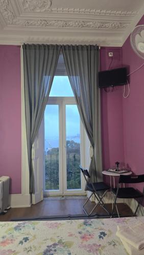 a room with a large window with a table and a desk at Cenário Catita Hostel in Lisbon
