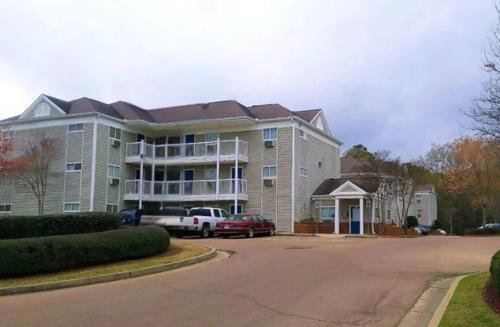 a large apartment building with cars parked in front of it at Birch Hill Suites Jackson in Jackson