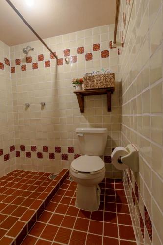 a bathroom with a toilet and a tiled floor at Casa Huitsiki in Cuetzalán del Progreso