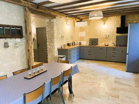 a large kitchen with a long table and chairs at Le chai de Peyssard, piscine chauffée. in Château-lʼÉvêque