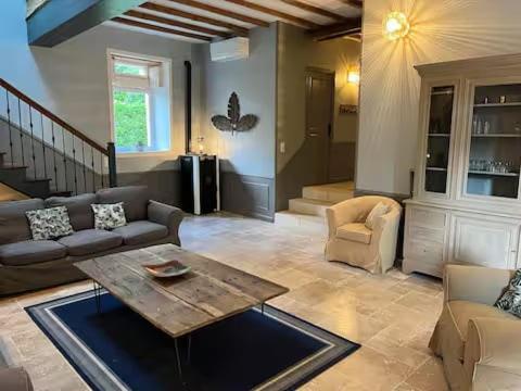 a living room with a couch and a table at Le chai de Peyssard, piscine chauffée. in Château-lʼÉvêque