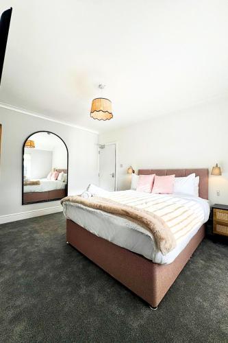 a bedroom with a large bed and a mirror at The Lockside By Allsquare Stays 5BDR Heathrow M4 M25 M3 in Staines