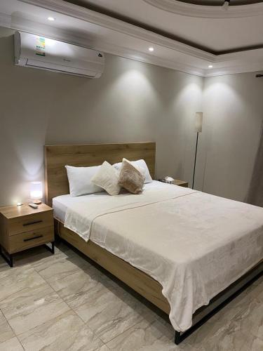 a bedroom with a large white bed and a night stand at Izdihar Dalis Suites in Quai