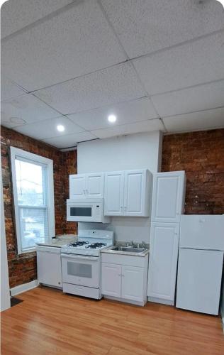 a kitchen with white appliances and a brick wall at Charm's City Cozy Studio in Baltimore