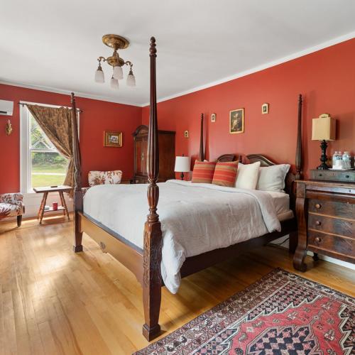 a bedroom with a bed with red walls and a dresser at The Mulburn Inn in Bethlehem