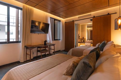 a hotel room with two beds and a desk at Hotel Agua de Plata in San Luis Potosí