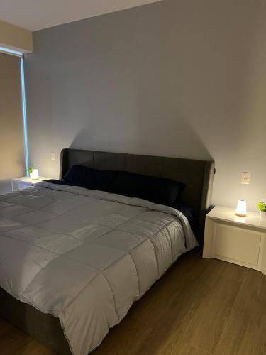 a bedroom with a large bed and two tables at Executive Loft - Gym - Home Office - Zibatá in La Cañada