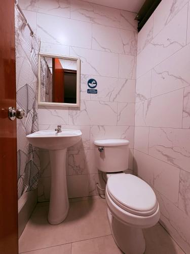a white bathroom with a toilet and a sink at HOTEL ALFONSO UGARTE in Chiclayo