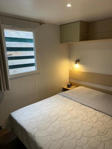 a bedroom with a large bed and a window at Mobil-home 1 in Quimper