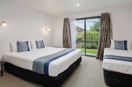 two beds in a room with a window at ASURE Phoenix Motor Inn in Blenheim