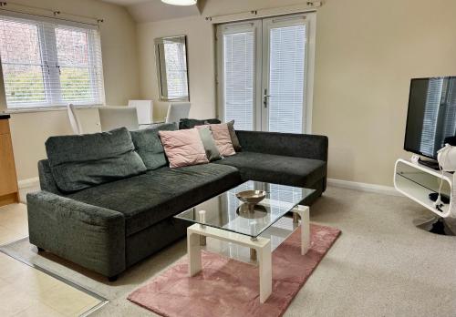 a living room with a black couch and a glass table at Quiet 2 Bedroom Apartment in Headington, Close to Oxford Hospitals & Brookes University in Oxford