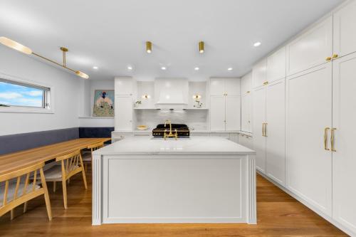 a kitchen with white cabinets and a wooden table at Luxury boutique bay retreat in Williamstown