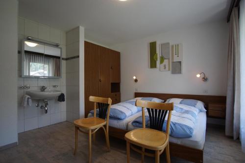 a bedroom with a bed and a sink and chairs at Haus Amor in Saas-Fee