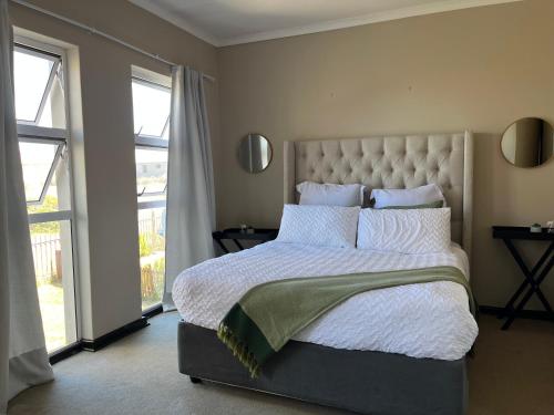 a bedroom with a large bed with white sheets and pillows at The Grey Ivory in Port Alfred