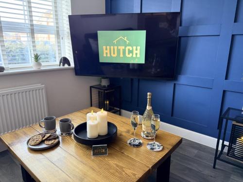 a wooden table with candles and wine glasses and a tv at Modern 2-Bed House with EV - Hosted by Hutch Lifestyle in Warwick
