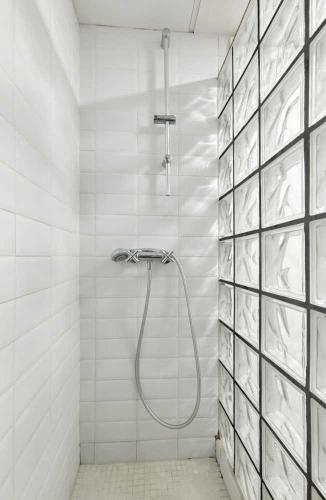 a shower with a hose in a white tiled bathroom at Alojamiento Simon 1 Murcia in Murcia