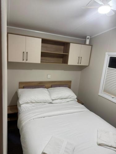 a bedroom with a bed with white sheets and a window at Oakley Newquay Bay Resorts in Newquay Bay Resort