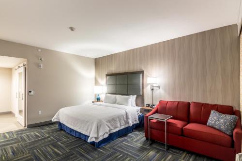 オクラホマシティにあるHampton Inn Oklahoma City Northeast OKのベッドと赤いソファのあるホテルの部屋