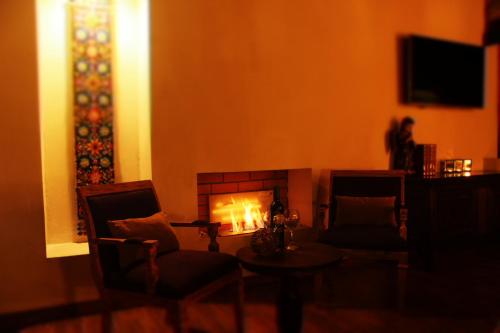 a living room with a fireplace and a table and chairs at Hotel Boutique La Casona de Don Porfirio in Jonotla