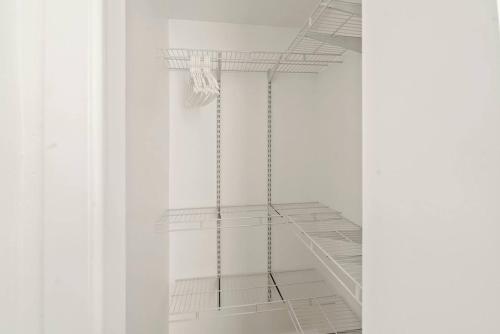 a white closet with white shelves in a room at Cozy Retreat 15Min to NYC, FIFA, Mall,FREE Parking - Apartment in North Bergen