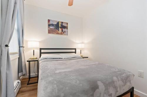 a white bedroom with a bed and two lamps at Cozy Retreat 15Min to NYC, FIFA, Mall,FREE Parking - Apartment in North Bergen