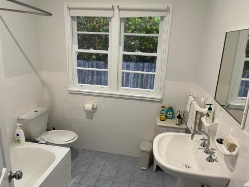 a white bathroom with a sink toilet and a window at Moruya Heads Constable Street in Moruya Heads