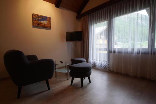 a living room with a chair and a stool and a window at Haus Amor in Saas-Fee