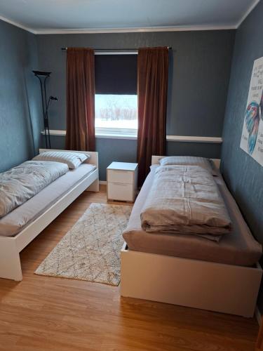 a bedroom with two beds and a window at Lyngen apartment in Lyngseidet