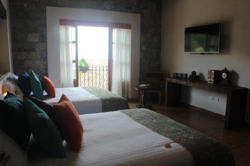 a hotel room with two beds and a television at Hotel Boutique La Casona de Don Porfirio in Jonotla