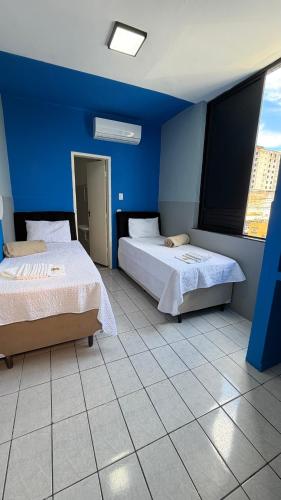 two beds in a room with blue walls at Hotel Brasilia in Aracaju