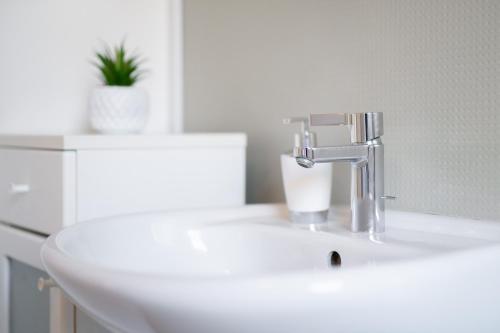 a white sink with a faucet on a bathroom at Orange Suite Schliengen 1 in Schliengen