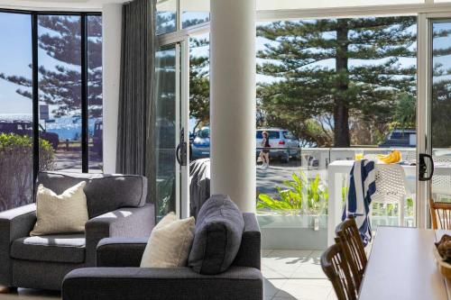 a living room with chairs and a table and windows at La Ronde One - Unit 1 - oceanstays in Yamba