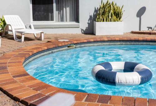 a swimming pool with a blue and white raft in it at La Ronde One - Unit 1 - oceanstays in Yamba