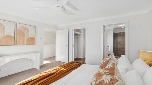 a white bedroom with a bed and a ceiling at The Haven - Ettalong in Ettalong Beach