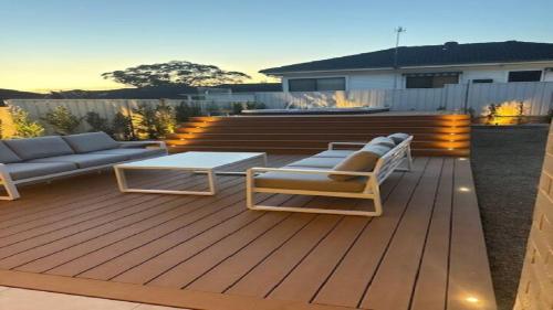 a deck with a couch and chairs and a table at The Haven - Ettalong in Ettalong Beach