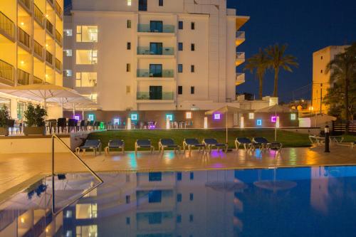 a swimming pool with chairs in front of a building at Hotel Luxor in Playa de Palma