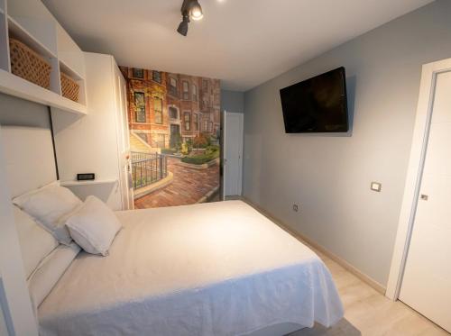 a bedroom with a white bed and a flat screen tv at Sevilla Family House - La casa de Marta in Montequinto