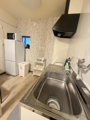 a kitchen with a sink and a refrigerator at Lee house 佳 別荘 一戸建て貸切の宿 in Osaka