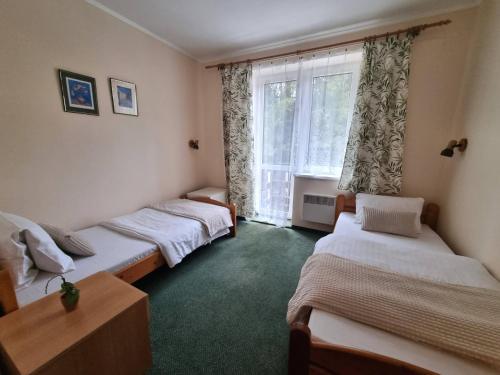 a group of three beds in a room with a window at Horský Hotel Magura in Chvojnica