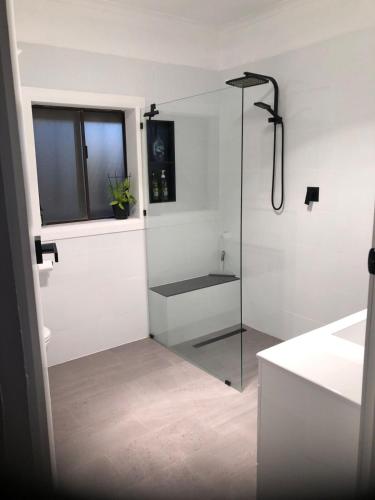a bathroom with a glass shower with a sink at StevieNic's Dig's in Broken Hill