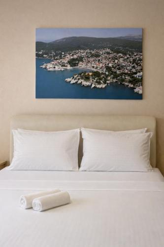 a bed with white pillows and a painting on the wall at Belmare in Ulcinj