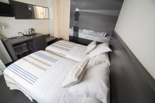 1 Schlafzimmer mit 2 Betten mit Kissen und einem Waschbecken in der Unterkunft Hostal Cabo Mayor in Santander