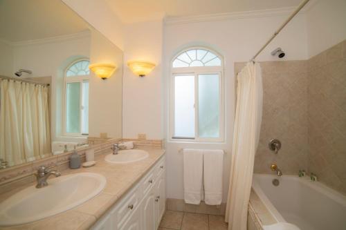 a bathroom with two sinks and a tub and a shower at Colina 5E 2 bdr Garden View in Los Suenos in Jacó